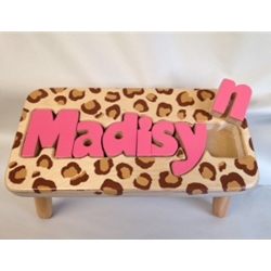 A leopard print kids stool with a name on it.